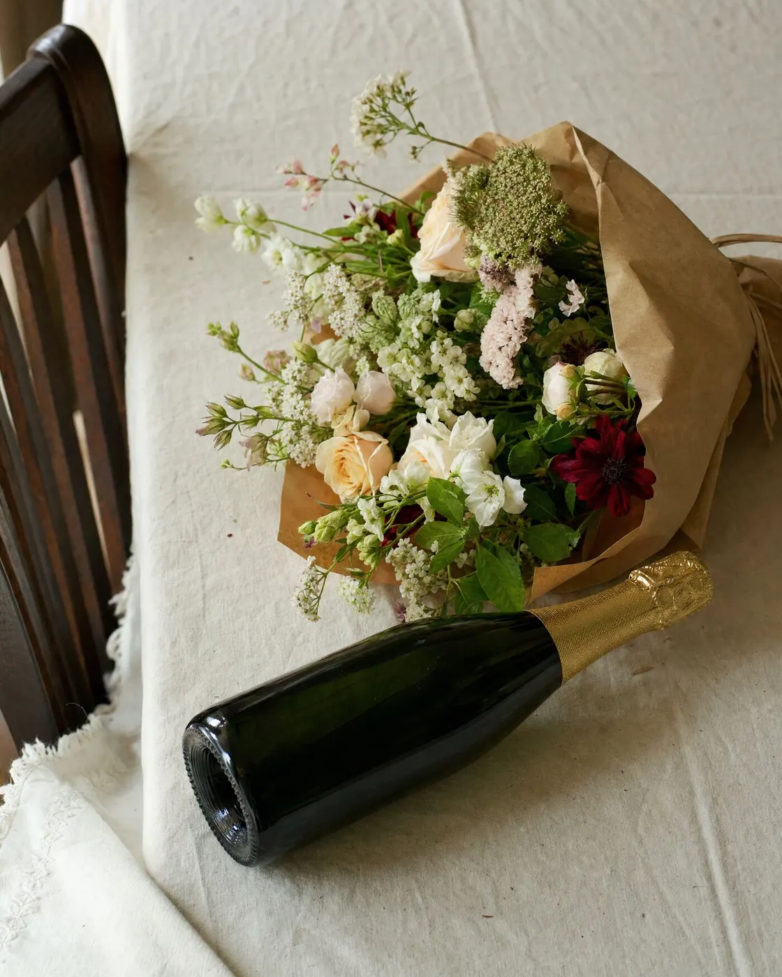 Een bos bloemen en een fles champagne op tafel